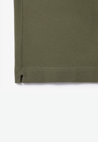 Tejido verde oliva con un tejido texturizado, que presenta un dobladillo recto y una pequeña abertura en la esquina inferior izquierda para un detalle añadido.