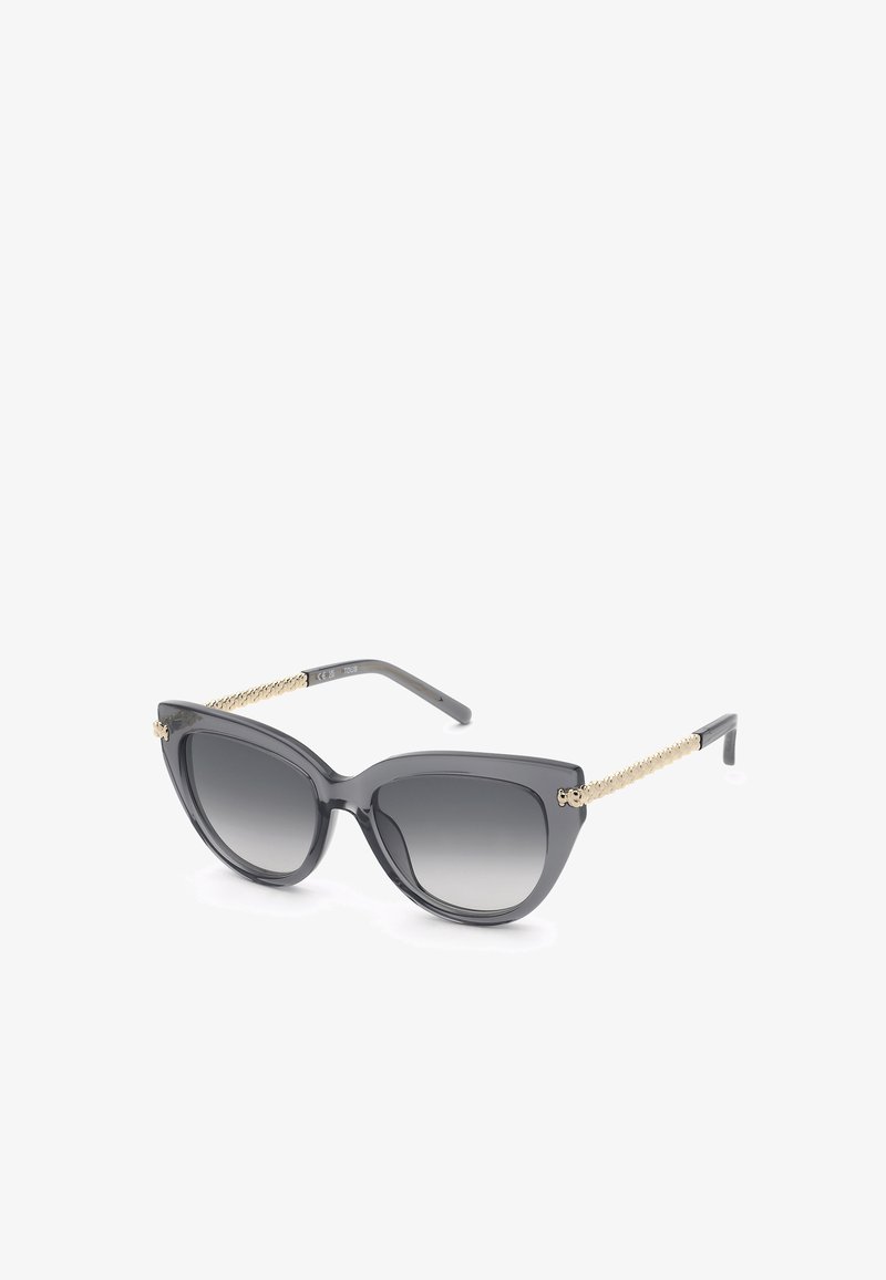 Lunettes de soleil œil de chat noires avec verres dégradés foncés et branches texturées chaîne dorée sur fond blanc.