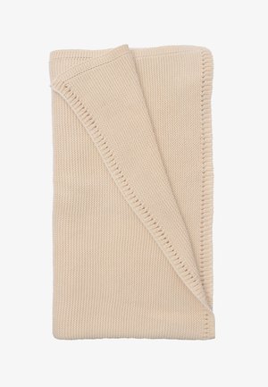 Knitted beige blanket folded diagonally, featuring a textured pattern and a neat stitched edge. Soft and warm fabric appearance.