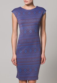 Robe sans manches ajustée en bleu et violet, présentant un motif géométrique de diamants et de lignes, fabriquée à partir d'un tissu lisse et extensible.