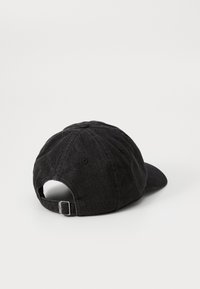 Casquette en denim noir avec une visière courbée, une sangle arrière ajustable et des détails cousus. Elle présente un tissu texturé avec des œillets de ventilation.
