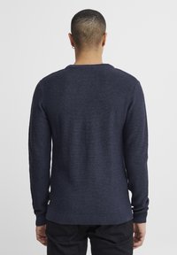 Maglione blu navy lavorato a maglia con polsini e orlo a coste. Presenta un motivo a trama e una scollatura rotonda. La vista posteriore mostra cuciture dettagliate.