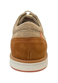 Chaussure en daim beige et mesh avec des accents orange, forme arrondie, semelle blanche et matériaux texturés contrastants. Marque Fluchos sur le talon.