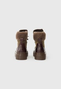 Botas con tacón de cuero marrón, parte superior de ante verde oliva y cuello de piel sintética. Presentan una gruesa suela de goma marrón y un diseño de cordones.