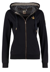 Sudadera con cremallera negra hecha de algodón con un interior de tela a rayas. Presenta una cremallera en tono dorado, cordones y bolsillos laterales.