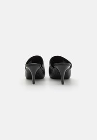 Chaussures à talons hauts en cuir noir avec une finition lisse, des pointes pointues et des talons aiguilles fins. Aucun matériel ou motif visible.