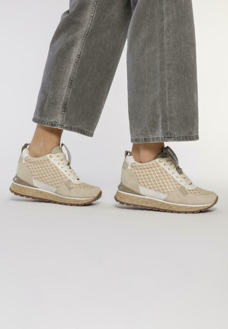 Zapatillas deportivas beige con un patrón de malla, acentos de ante y una suela texturizada, con un perfil bajo y un talón acolchado.