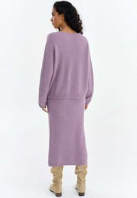 Liliowy sweter z dzianiny oraz dopasowana spódnica, miękka faktura, luźny krój, długie rękawy, długość do kostek. Połączone z beżowymi kozakami za kolano.