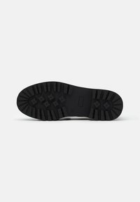 Sole di scarpa in gomma nera con superficie texturizzata e battistrada profondo, caratterizzata da motivi a stella per trazione e stabilità.
