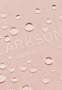 Tessuto rosa con texture e gocce d'acqua, con marchio in rilievo "CLARKSON HAMBURG", che evidenzia le sue caratteristiche impermeabili.