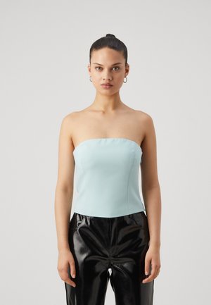 Light blue strapless top with a fitted design. The material appears smooth and stretchy, paired with high-shine black leather pants.