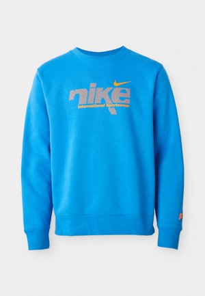 Blue sweatshirt made of cotton blend, featuring a large gray Nike logo and "International Sportswear" text in orange below. Long sleeves.