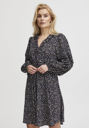 Ein floral gemustertes Kleid aus marineblauem Stoff. Verfügt über eine Knopfleiste, lange Puffärmel und eine taillierte Taille, die eine lässige Passform schafft.