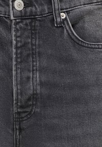 Close-up of black denim jeans showing waistband, button, zipper area, belt loop, and top edge of front pocket.
