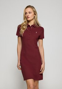Burgundowa sukienka polo wykonana z miękkiej bawełny, z kołnierzykiem, krótkimi rękawami, sześcioma guzikami z przodu i małym haftowanym logo na piersi.