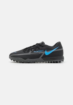 Zwarte Nike Phantom voetbalschoen met blauw logo en gestructureerde zool voor kunstgrasvelden, zijaanzicht op witte achtergrond.