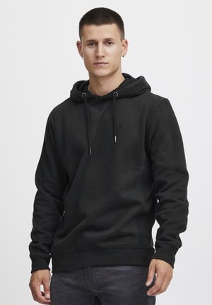 Hoodie en coton noir avec cordon de serrage, poignets et ourlet côtelés. Logo discret sur la poitrine. Texture lisse, coupe décontractée.