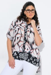 Short-sleeve blouse featuring a black and white patterned lower half, pink and gray abstract print on the top, with a button-down design.