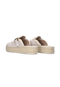 Beige suède slip-ons met open achterkant, voorzien van een gevlochten juten zool, met een gespstrap en geschulpte randdetails.