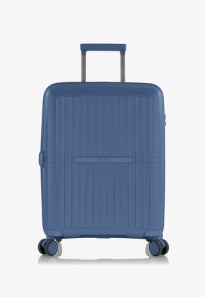 Blauwe harde koffer met verticale ribbelstructuur, uitschuifbare handgreep, vier wielen en een ritscompartiment. Kenmerkt het HEYS-logo.