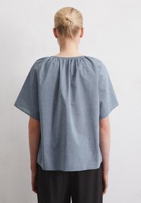 Top azzurro chiaro a maniche corte con scollo arricciato e vestibilità rilassata. Texture morbida, orlo arrotondato e design semplice per una versatilità d'uso.