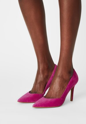 Helle pinke Wildleder-Pumps mit spitzem Zeh und schlankem Stiletto-Absatz, die eine glatte Textur und klare Designlinien zeigen.