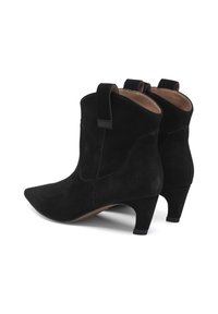 Botas de tobillo de ante negro con punta afilada, tacón bajo y tiradores laterales. El diseño presenta líneas limpias y sutiles acentos de costura.
