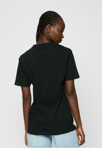 Black cotton t-shirt with short sleeves, a crew neckline, and a relaxed fit. Simple design with no visible patterns or embellishments.