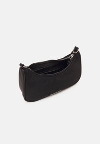 Pequeño bolso negro con cremallera y bandolera, con anillos de metal plateado y compartimentos interiores, sobre un fondo blanco liso.