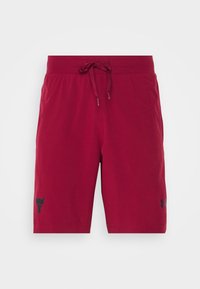 Pantalones cortos deportivos rojos fabricados con un tejido ligero. Presentan una cintura elástica con cordón y un detalle de logo negro en la pierna izquierda.