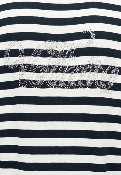 Υφασμα οριζόντιες ασπρόμαυρες ρίγες με τη λέξη «Vallauris» περιγραμμένη με μικρές ασημένιες καρφίτσες στο κέντρο.