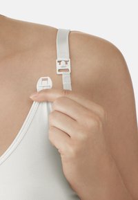 Weißer BH-Träger mit verstellbarem Slider und Clip, glattes Material, runder Ausschnitt. Hand hält den Träger nah am Befestigungspunkt.