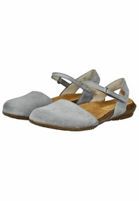 Graue Wildlederschuhe mit flacher Sohle, die über Kreuzriemen, offene Seiten und eine runde Zehenpartie verfügen. Die Innensohle hat eine hellbraune Farbe.