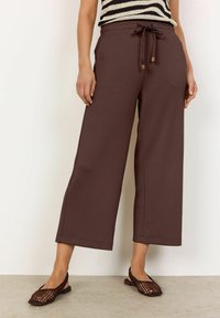Brune brede sweatpants med elastisk talje og snøre. Blød tekstur og glat stof med en afslappet pasform.