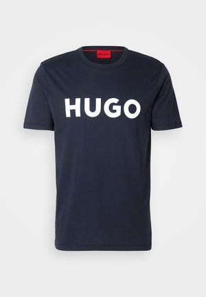 Marineblå bomulls t-skjorte med en stor hvit "HUGO" logo på forsiden, rund hals og korte ermer. Rød innvendig etikett.