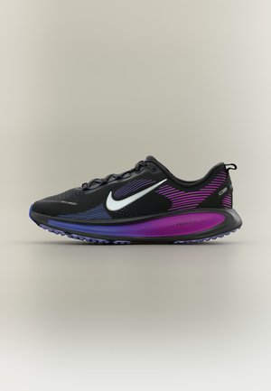 Chaussure de course Nike noire et violette avec un swoosh blanc, une semelle texturée et un marquage "React" sur la semelle intermédiaire rembourrée.