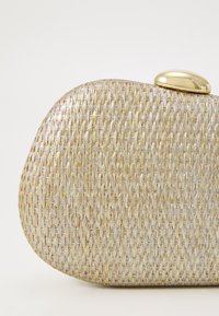 Bolso de mano metálico tejido en tonos plateados y dorados, con una forma redondeada y un cierre en tono dorado. Superficie texturizada.