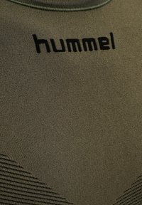 Grön kortärmad atletisk skjorta för män i strukturerad tyg, med svart "hummel"-logotyp på bröstet och subtilt randigt mönster.