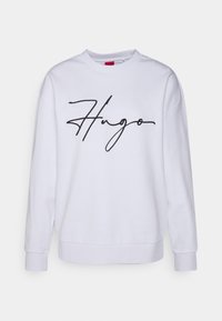 Felpa bianca con scollatura a girocollo, maniche lunghe e un logo "Hugo" nero scritto in corsivo stampato sul davanti. Il materiale appare morbido e liscio.