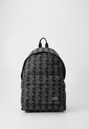 Black backpack with a geometric pattern and gray accents. Features a top handle and adjustable straps. Recessed zipper pocket on front.