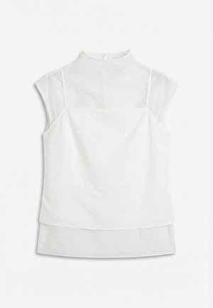 Vit ärmlös lager-på-lager-blus med genomskinlig överdel och hög krage, utlagd mot en vit bakgrund.