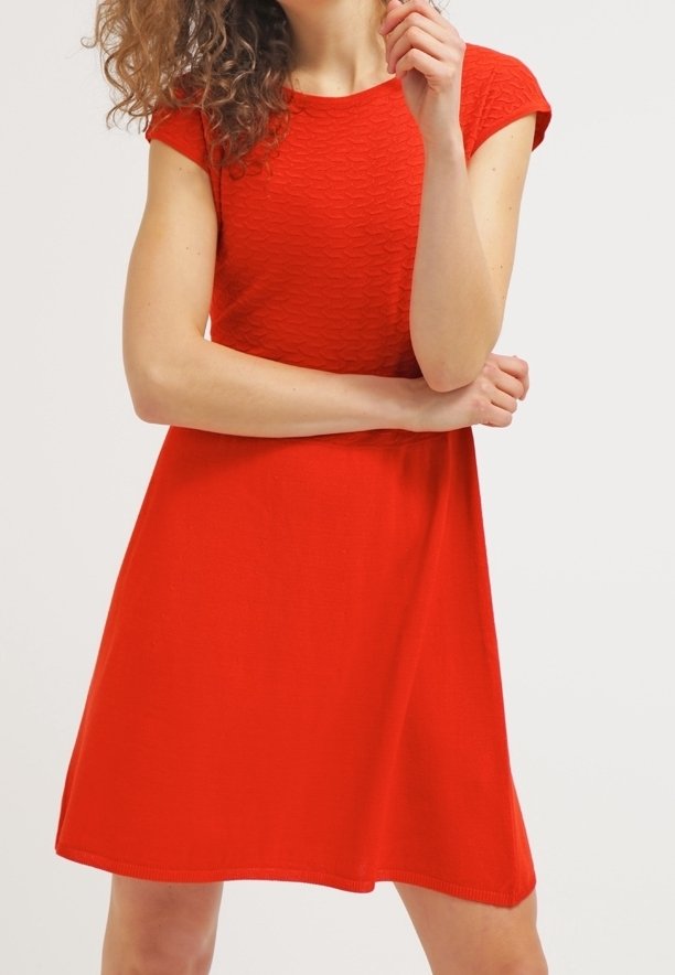 Röd stickad klänning med ett texturerat mönster, korta ärmar och en utsvängd nederdel. Slät tyg, avslappnad design, knälång, utan synliga dekorationer.