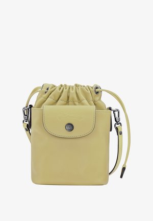Yellow leather drawstring bag featuring a flap with a logo, adjustable strap, and metallic accent. Smooth texture and compact design.