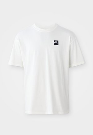 Weißes Baumwoll-T-Shirt mit kurzen Ärmeln und Rundhalsausschnitt; zeigt ein kleines schwarzes rechteckiges Nike Air-Logo auf der linken Brust.
