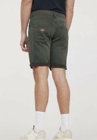 Shorts vert foncé en mélange de coton, avec des ourlets retournés, des poches arrière avec un détail en patch en losange et une coupe décontractée.