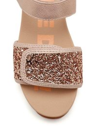 Sandalo in pelle tan con una larga fascia rivestita di glitter rosa oro. Suola liscia con testo stampato sotto la fascia.