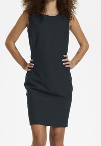 Knälång, mörkgrå klänning i mjukt tyg. Har en ärmlös design och böjda sömmar vid ringningen och sidorna.