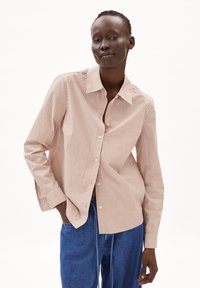 Camicia button-up a righe in marrone chiaro e bianco, con colletto, maniche lunghe e una vestibilità rilassata, abbinata a jeans in denim blu.