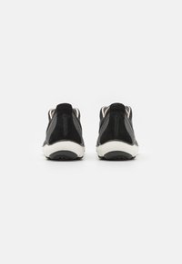 Schwarze Wildleder- und Mesh-Sneaker mit einer gepolsterten Sohle, ausgestattet mit einer Zuglasche hinten und einem minimalistischen Design. Akzentuierende Kontrastnähte sind vorhanden.