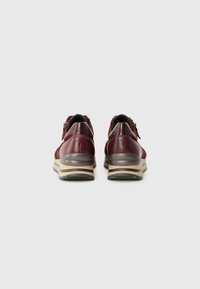 Chaussures en cuir rouge à texture lisse, de forme arrondie, avec des semelles rehaussées de beige. Dotées d'un petit talon et d'une fermeture éclair sur le côté.